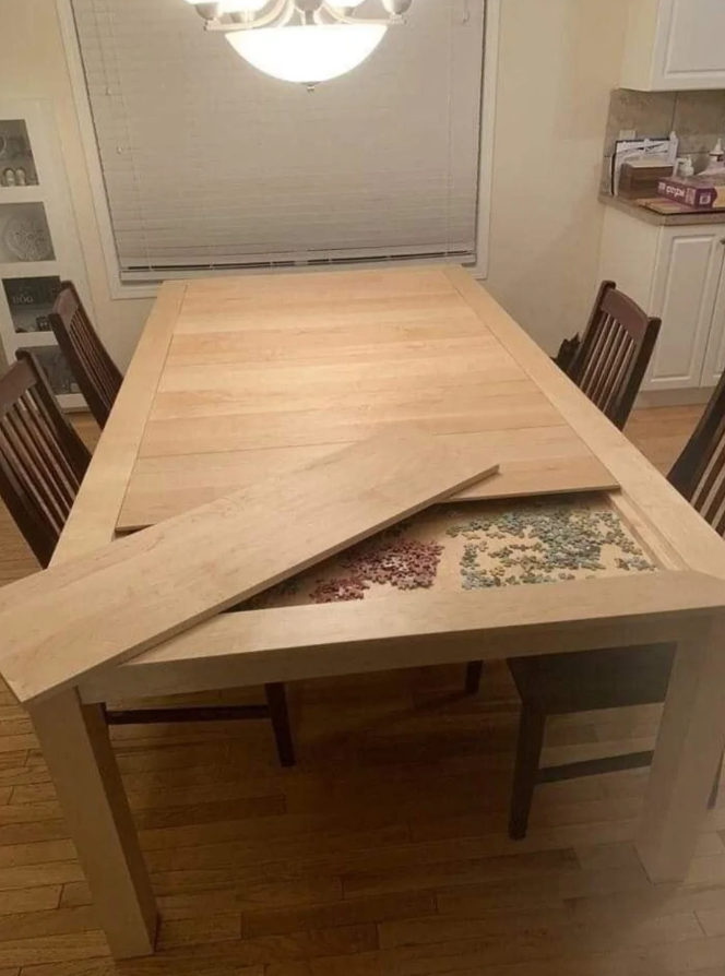 Drevený stôl s odnímateľnou doskou odhaľujúci rozložené puzzle dieliky v krásnej príjemnej jedálni.