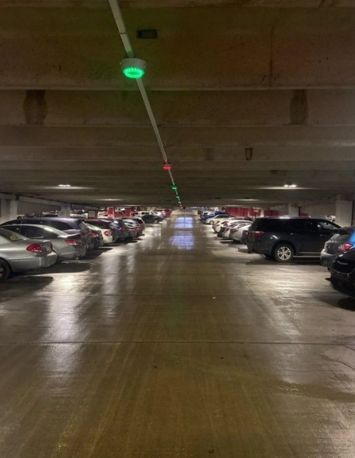 Podzemné parkovisko s autami, zelené a červené svetelné indikátory nad parkovacími miestami.