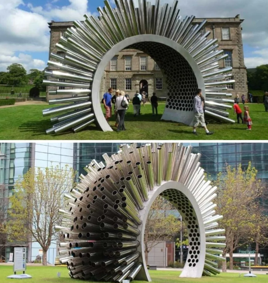 Moderná kovová socha v tvare oblúka z rúrok v parku, ľudia obdivujú jej dizajn pod slnečnou oblohou.