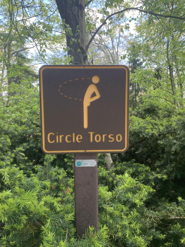 Značka na cvičenie trupu v parku, obklopená zeleňou.