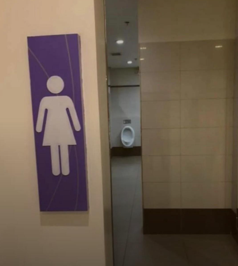 Značenie ženských toaliet vedľa pisoára, interiér verejnej toalety.