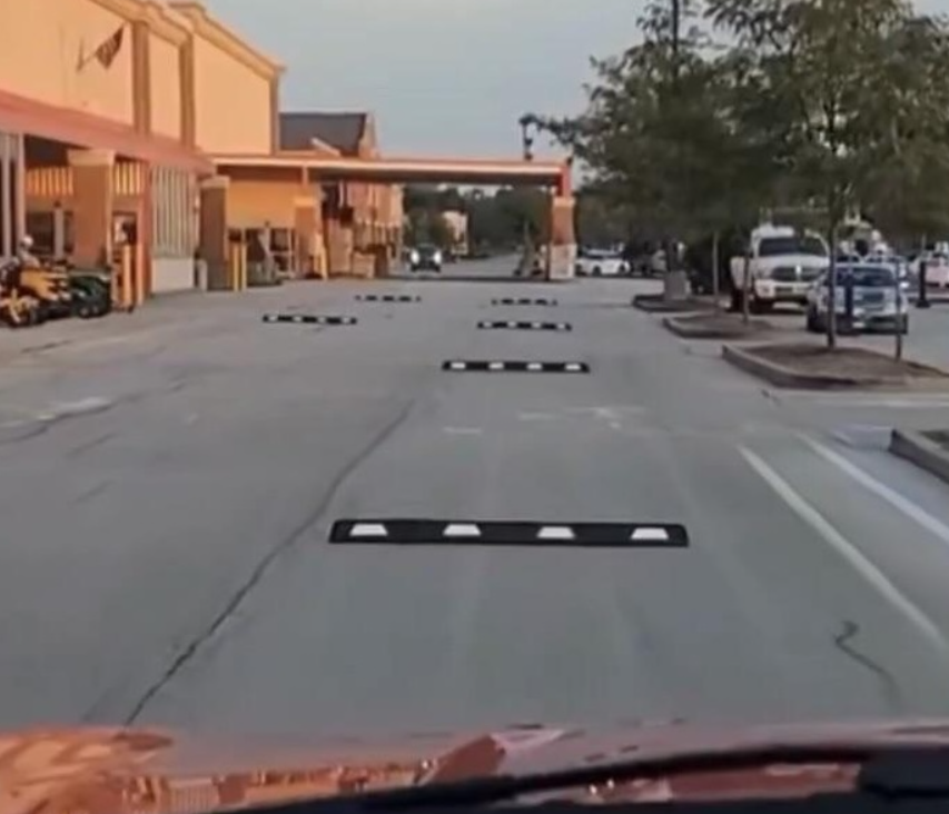 Cesta pri obchode s nalepenými spomaľovačmi, ktoré vyzerajú namaľované ako optická ilúzia.