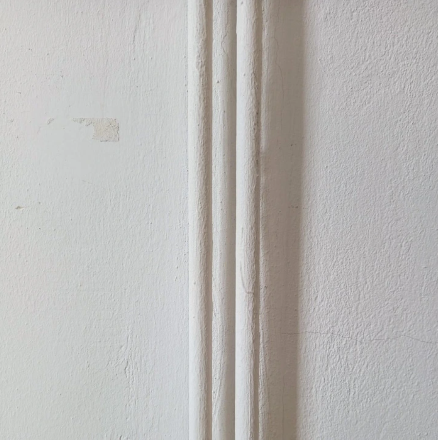 Textúra bielej steny s tromi vertikálnymi lištami na dekoračné účely.