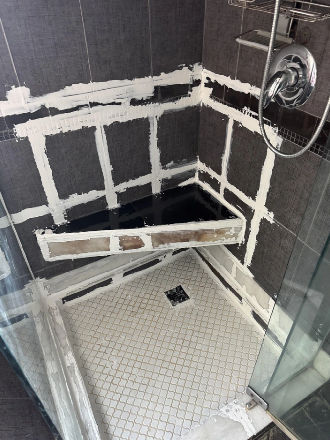 Sprchový kút v procese renovácie s novou škárovacou hmotou medzi dlaždicami a prvkami.