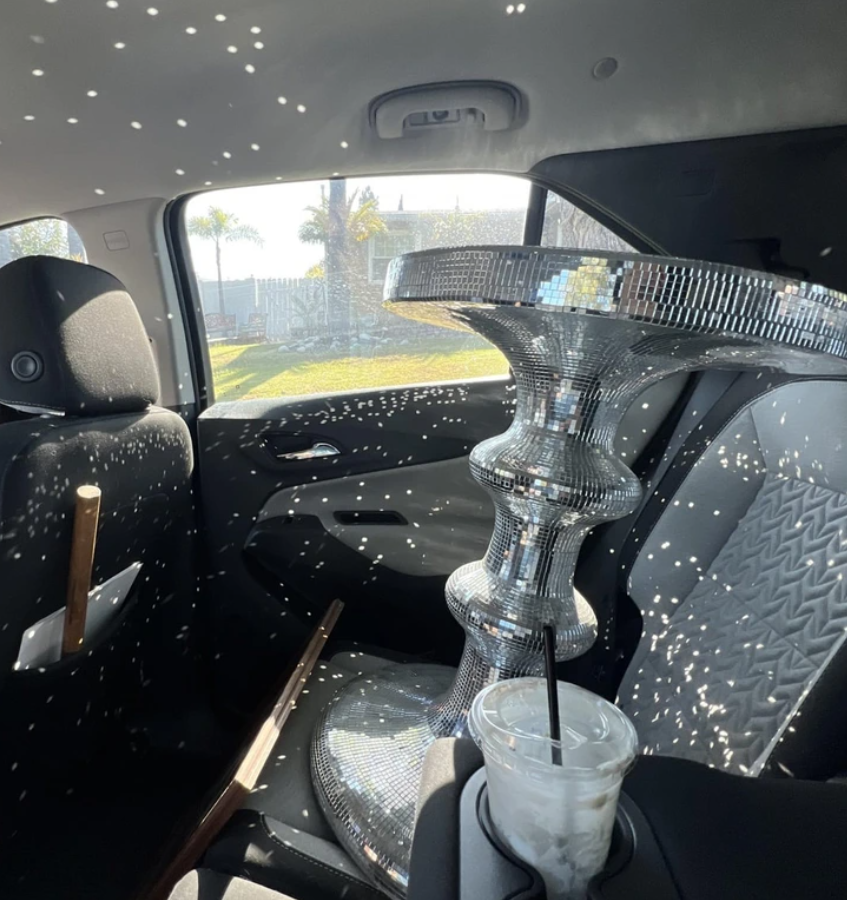 Dizajnový stolík z diskotékovej gule v zadnej časti auta vytvára svetelné odlesky na sedadlách.