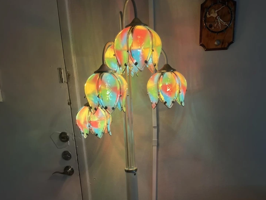 Farebná lampička v tvare kvetu s viacerými ramenami osvetľuje miestnosť jemnými odtieňmi dúhy.