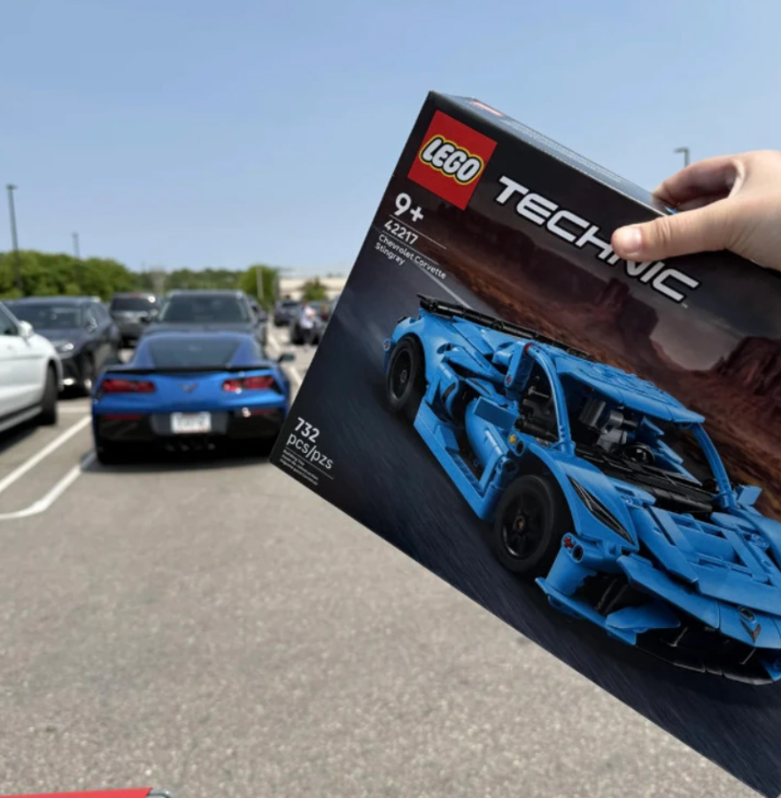 Krabica LEGO Technic Chevrolet Corvette pred modrým športiakom na parkovisku.
