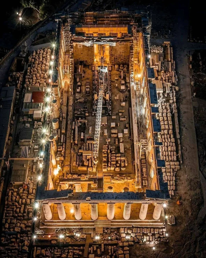 Letecký pohľad na nočnú rekonštrukciu starovekého chrámu s osvetlenými ruinami a staveniskom.