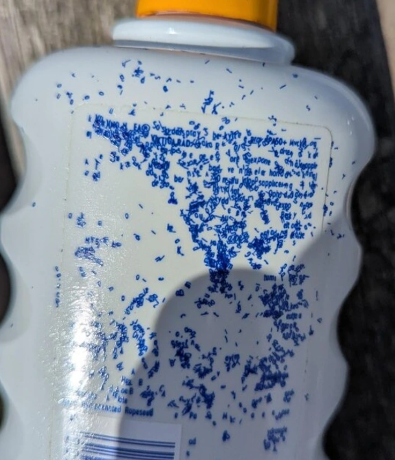 Nádoba so žltým uzáverom a rozmazaným modrým textom na etiketách.