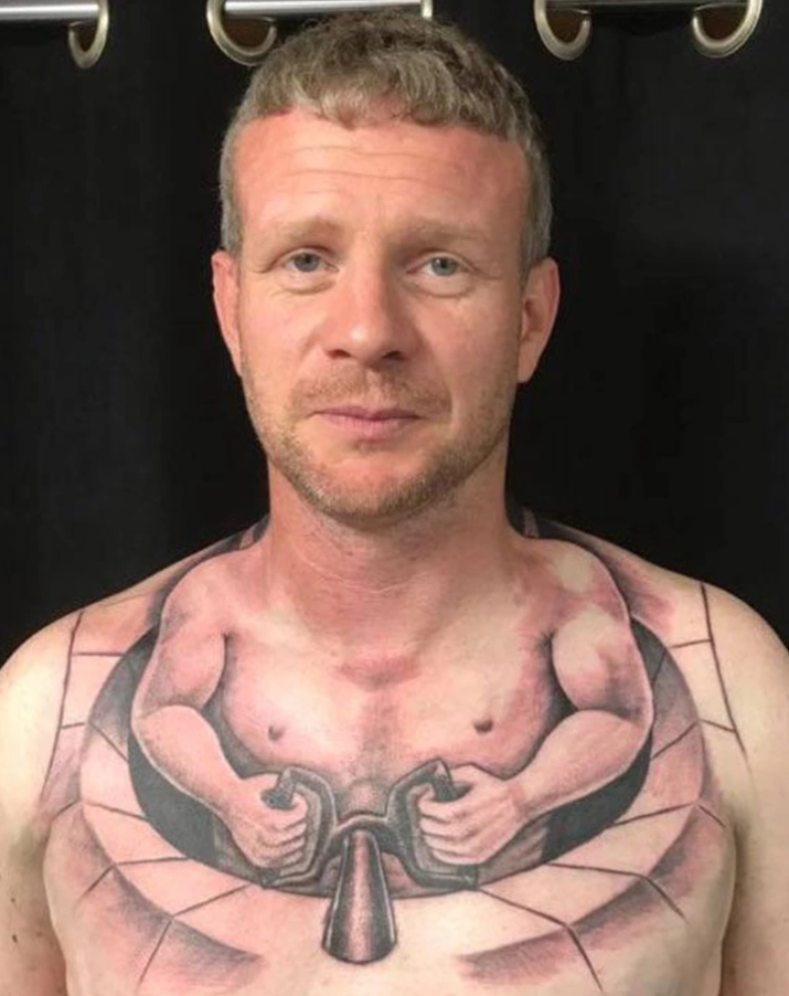 Osoba s kreatívnym tetovaním na hrudi s motívom kulturistu.