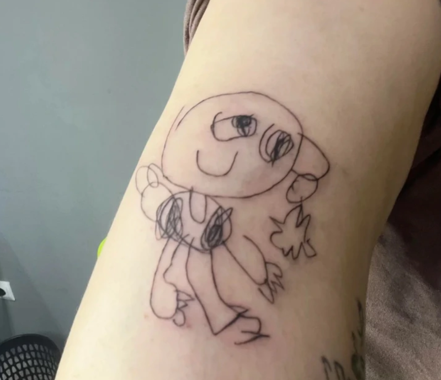 Jednoduchá detská kresba postavičky vytetovaná na ruke, znázorňujúca úsmev a veľké oči.