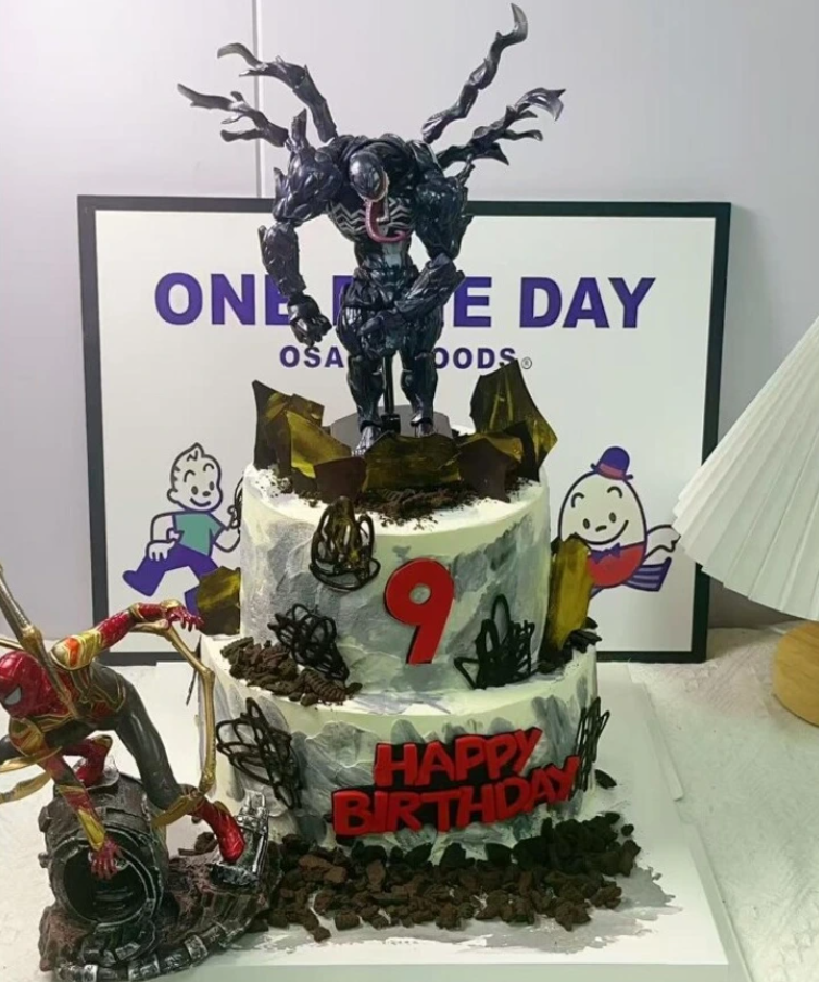 Narodeninová torta s modelmi superhrdinov a číslom deväť, ozdobená nápisom Happy Birthday.