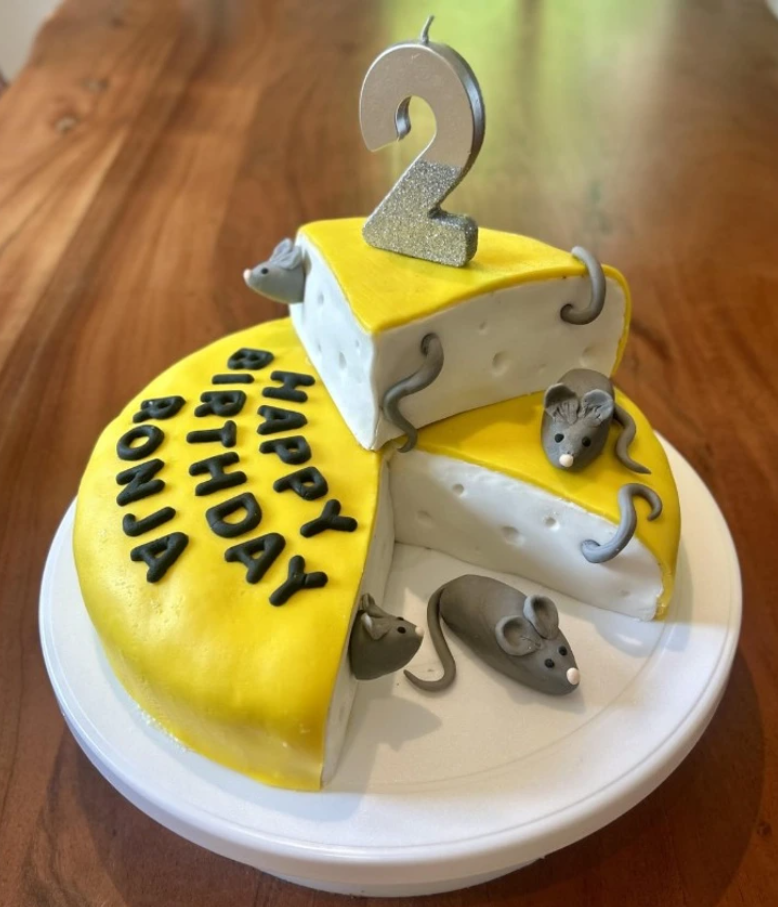 Detská narodeninová torta v tvare ementálu s myškami a sviečkou v tvare čísla dva.