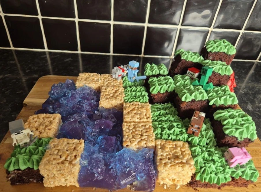 Domáca torta inšpirovaná Minecraftom s postavičkami a terénom z kakaového korpusu, cereálií a modrého želé.