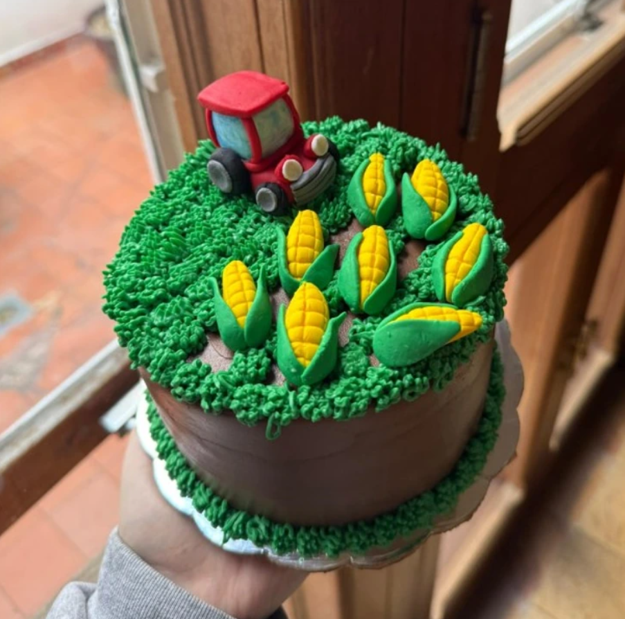 Torta s motívom farmy, ozdobená traktorom a kukuricou z fondánu, vhodná pre milovníkov poľnohospodárstva.