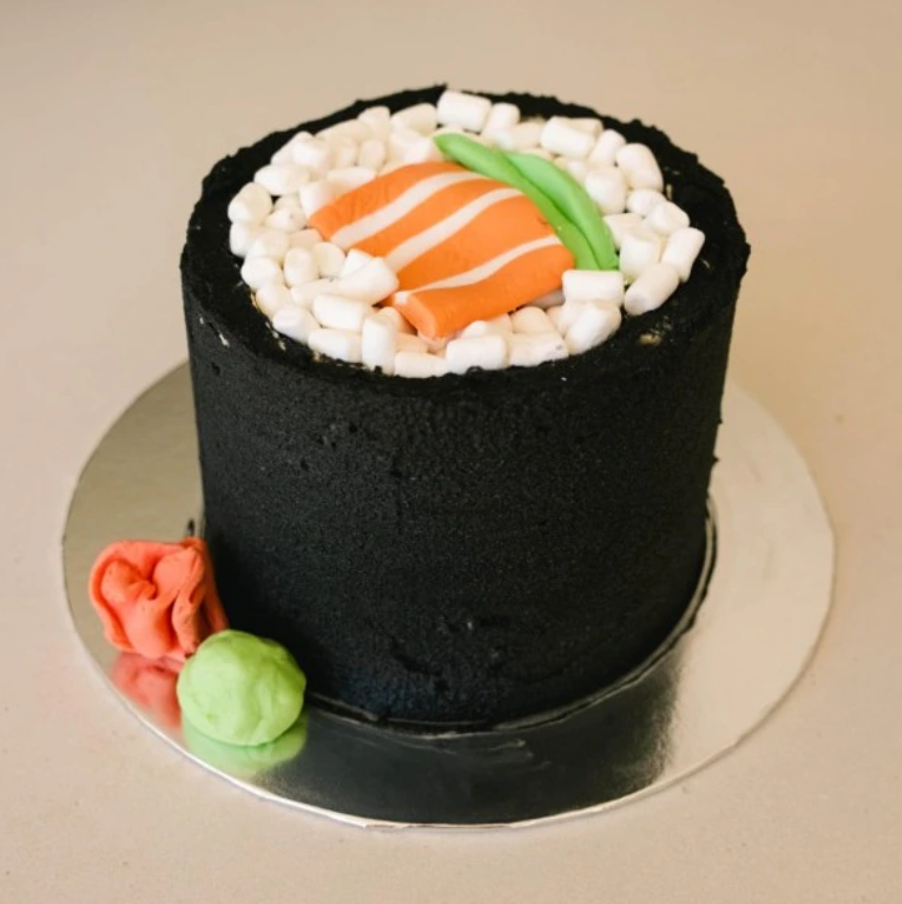 Torta v tvare sushi s lososom a avokádom, ozdobená fondánom. Originálny dezert pre milovníkov japonskej kuchyne.