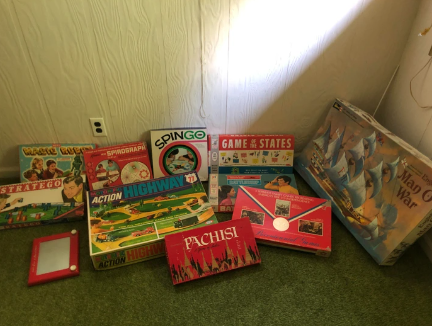 Klasické stolové hry na podlahe. Retro balenia hier ako Stratego, Pachisi a ďalšie sú usporiadané na zelenom koberci.
