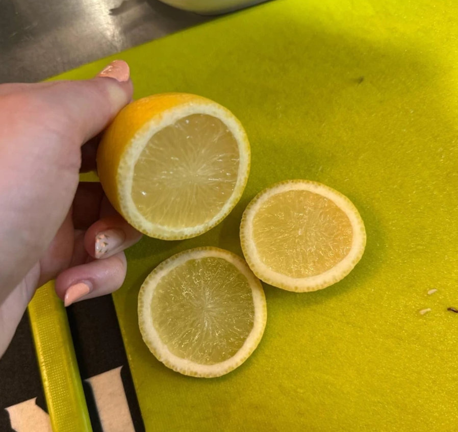 Čerstvý citrón nakrájaný na plátky na zelenom doske, pripravený na použitie v receptoch alebo nápojoch.