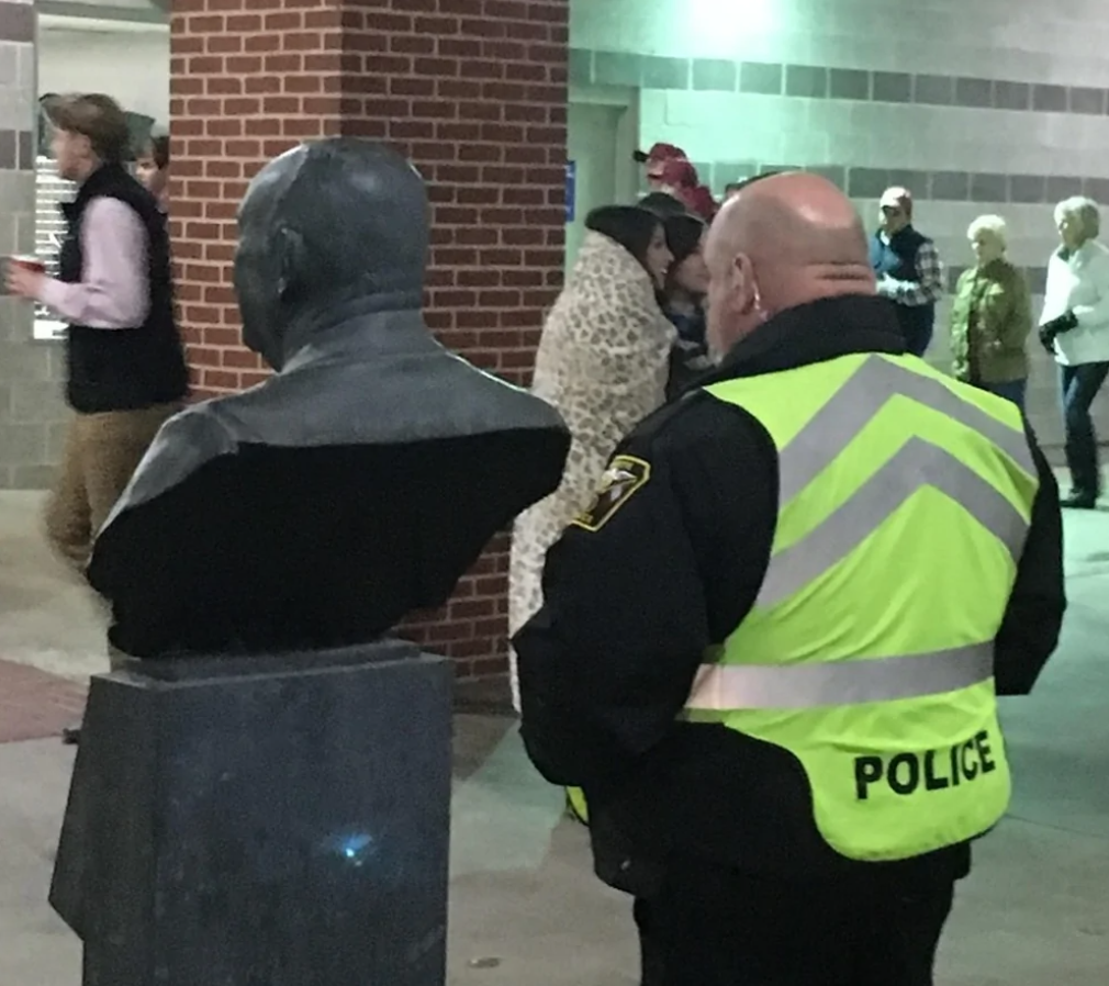 Pózujúca plastika a policajt v reflexnej veste pri výstavnej stene. Obohaťte SEO optimalizáciou webovú stránku.