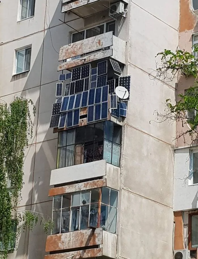 Bytový balkón s množstvom solárnych panelov na staršej budove, inštalované pre dodatočnú energiu.