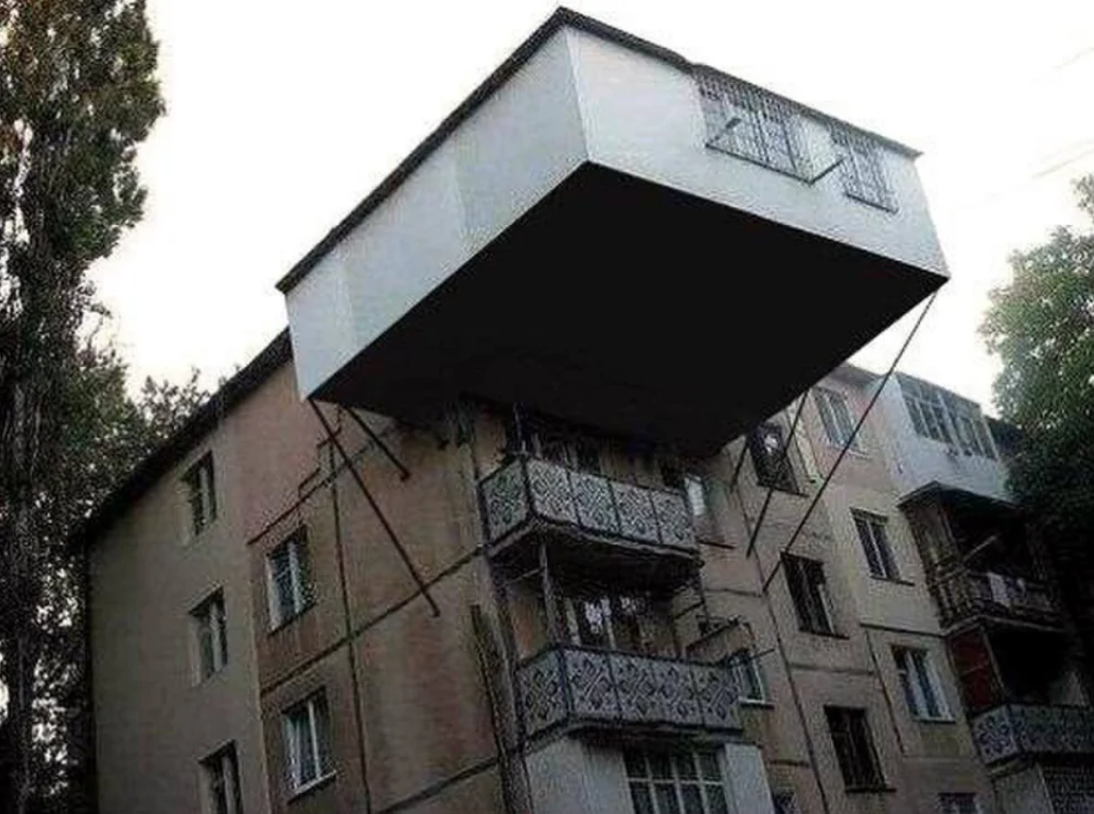 Budova so zväčšenou hornou časťou, ktorá vyčnieva nad balkóny, udržiavaná vzperami.