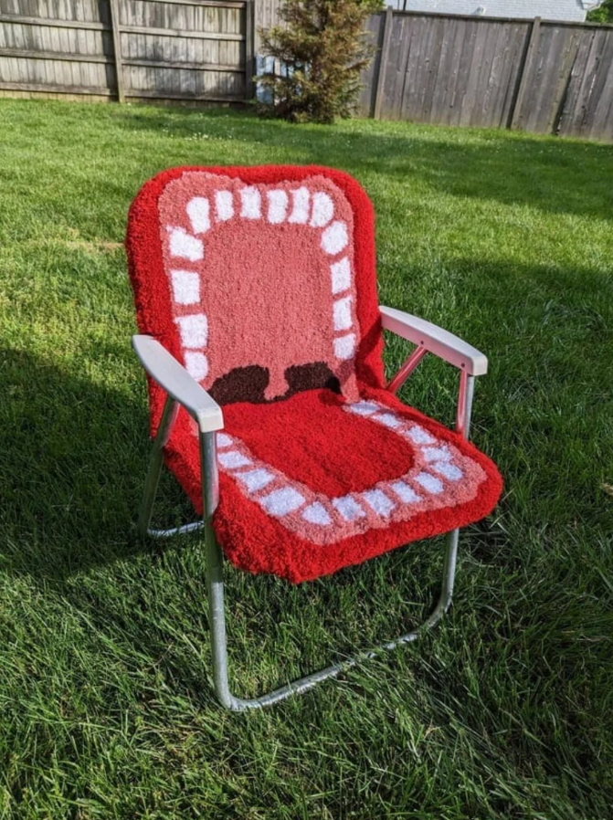 Kreslo s kobercovým poťahom v dizajne otvorených úst, umiestnené na tráve v záhrade.