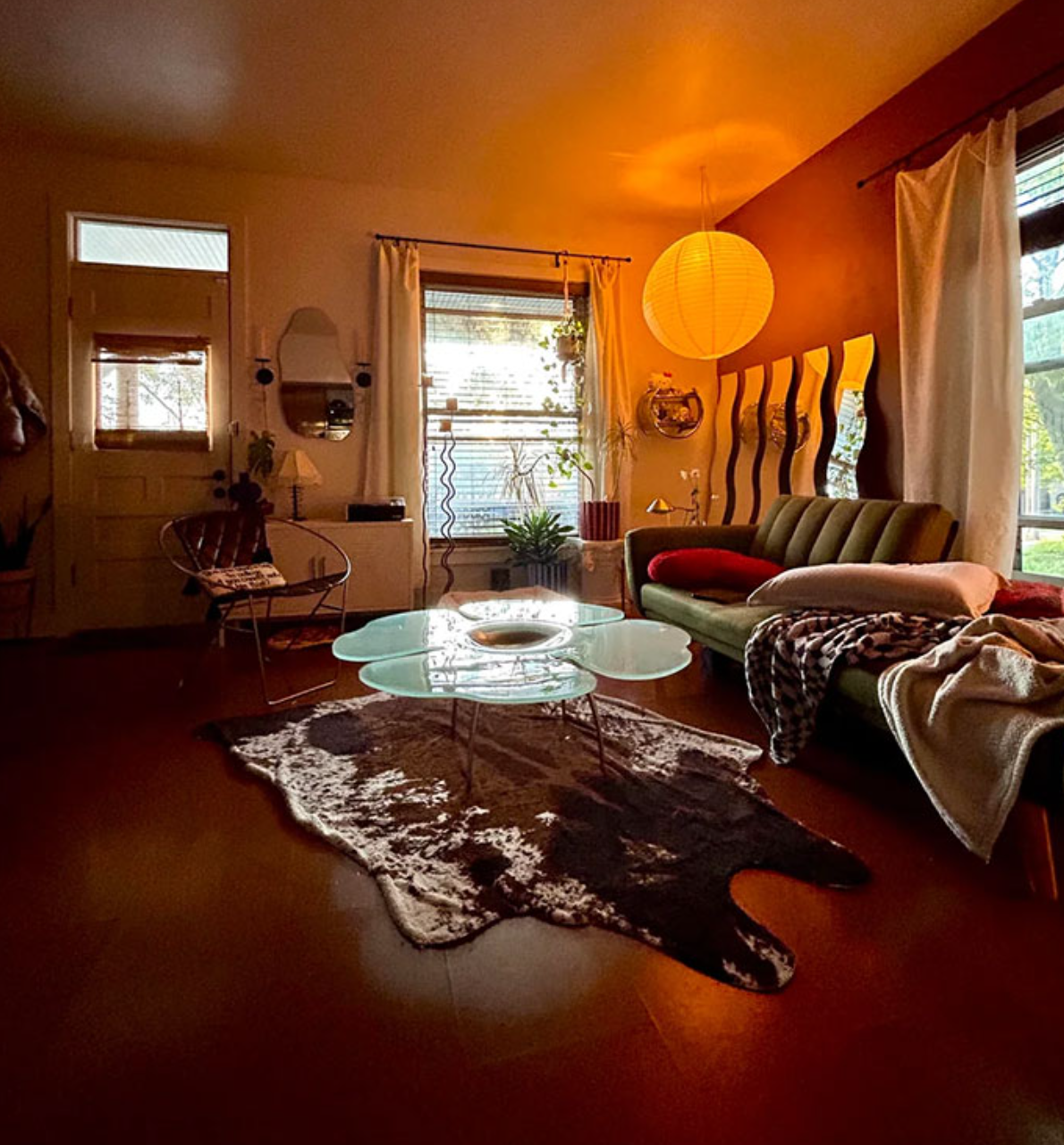 Útulná obývačka s moderným nábytkom, skleneným stolíkom a dekoráciou v teplých tónoch.