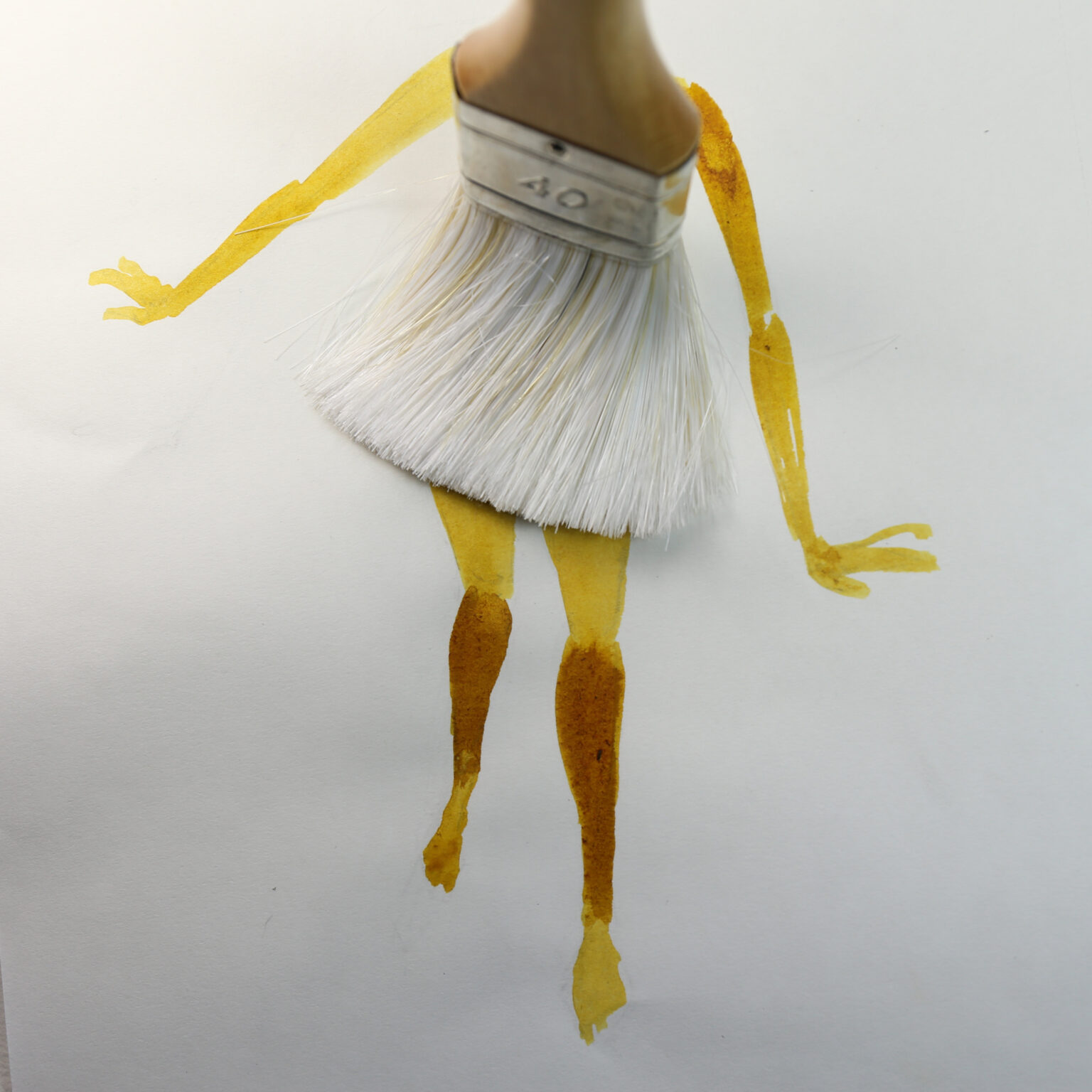 Štetec ako sukňa s namaľovanými žltými ramenami a nohami na bielom papieri. Kreatívna ilustrácia.