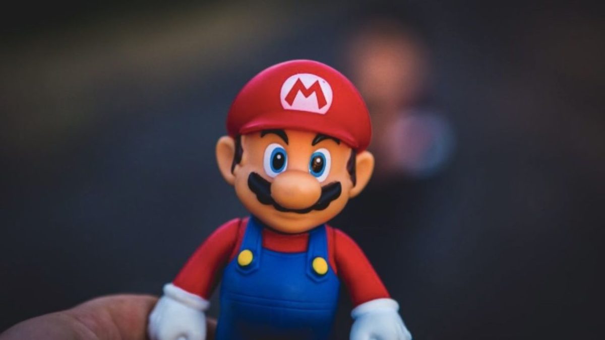 Hračka inšpirovaná slávnou postavou z videohry, držiaca kýmisi, na neostrom pozadí.