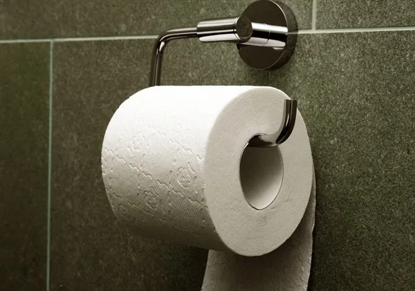 Toaletný papier na držiaku v kúpeľni na tmavosivom pozadí.