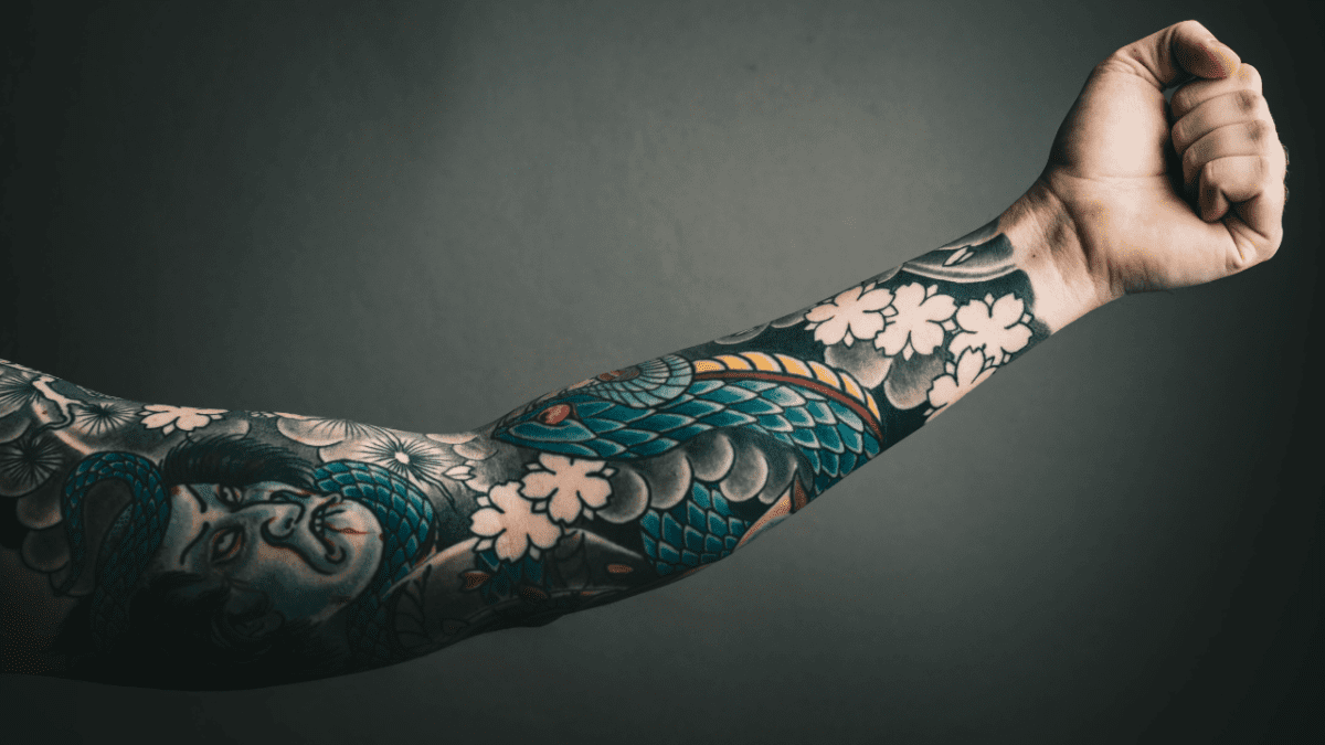 Tetovanie na predlaktí s japonským motívom draka a kvetov.