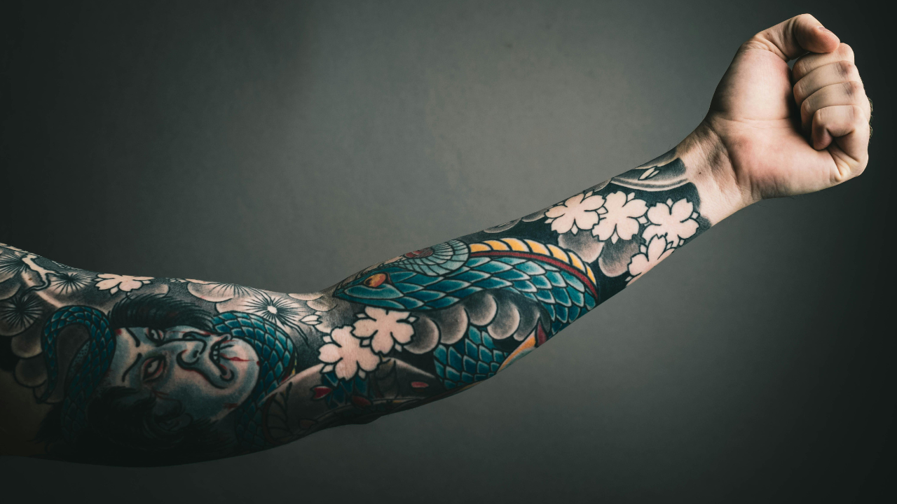 Tetovanie na predlaktí s japonským motívom draka a kvetov.