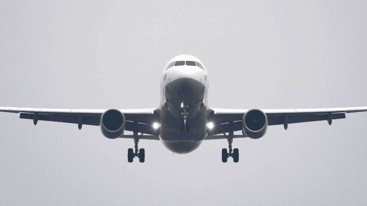 Pristávajúce dopravné lietadlo s rozsvietenými svetlami na zamračenom nebi.