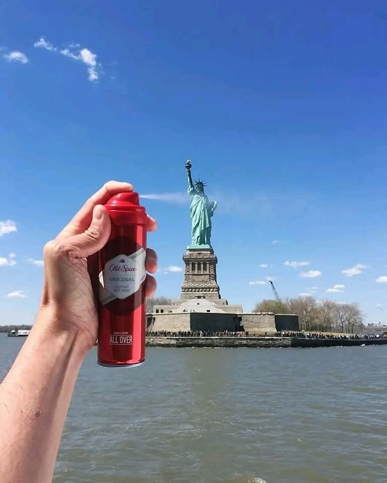 Deodorant v ruke pred Sochou slobody na jasnom oblohe vtipne kombinuje voľne stojace objekty.