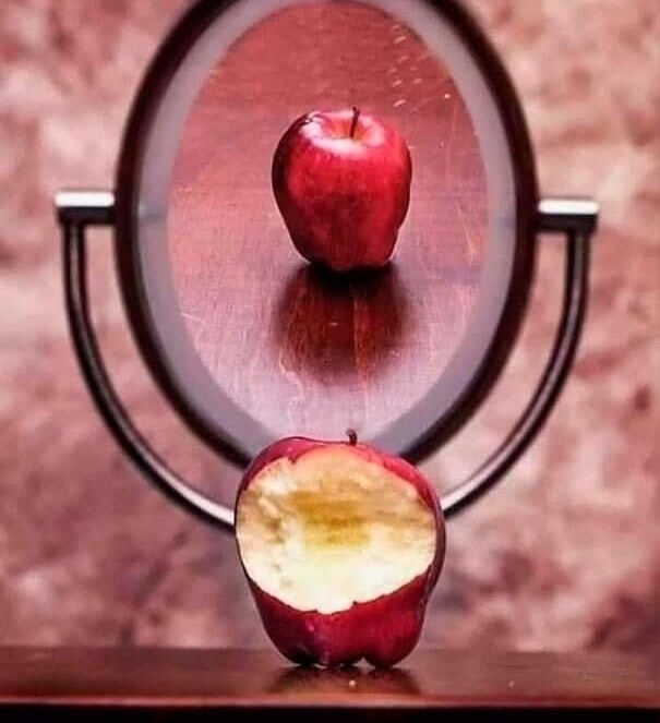 Zrkadlo ukazuje celé jablko, hoci pred ním je nakusnuté, na dřevěnom stolíku, symbolizuje vnímanie a ilúzie.