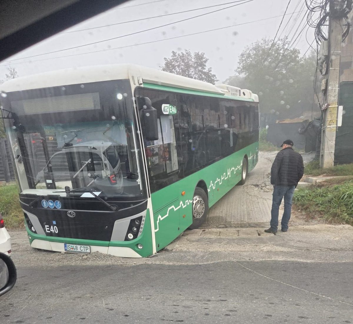 Autobus uviazol v prepadnutej ceste, človek vedľa neho stojí a zvažuje situáciu.
