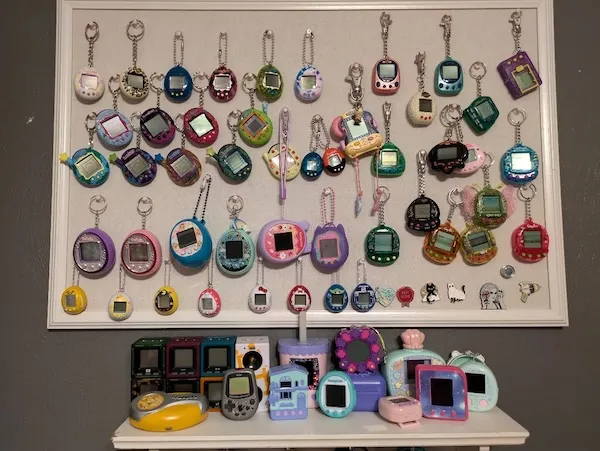 Zbierka retro Tamagotchi na stene a poličke, rôzne farebné verzie a modely týchto populárnych digitálnych zvieratiek.