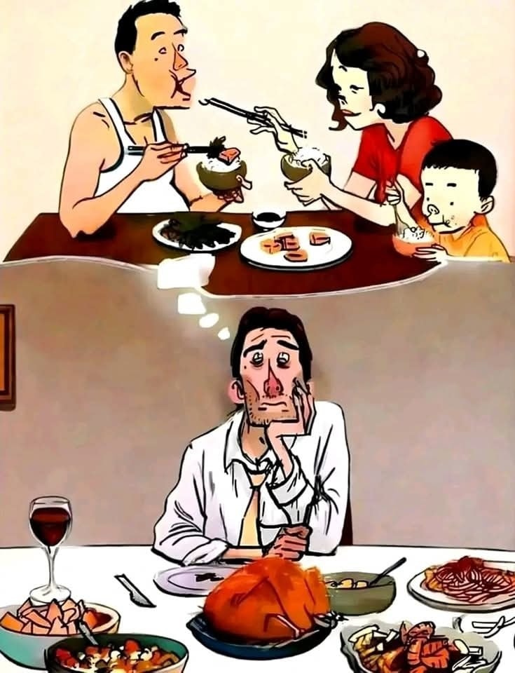 Muž sníva o rodinnej večeri, aj keď je pri bohato prestretom stole; kontrast osamelosti a spoločného času.