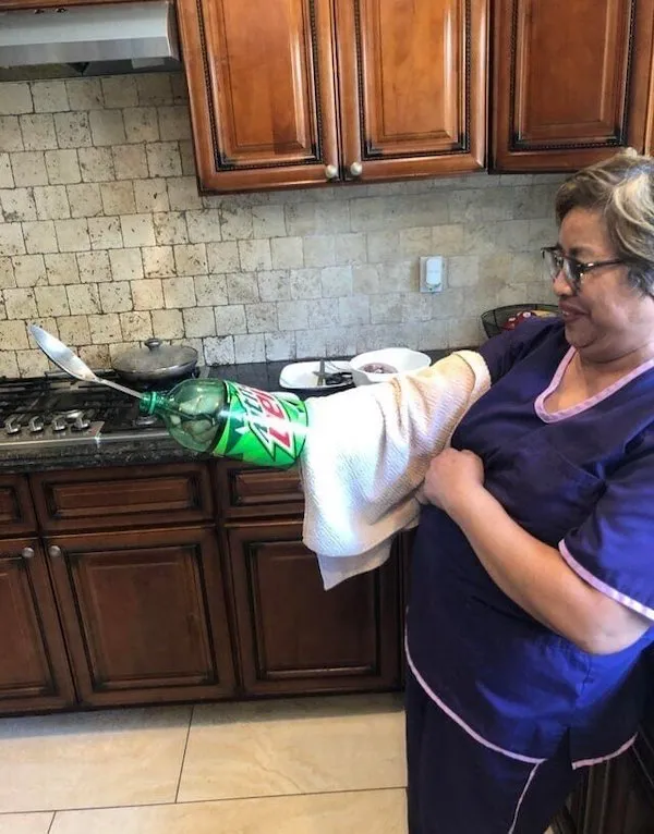 Žena v kuchyni používa kreatívnu pomôcku z fľaše na podopretie lyžice pri varení.