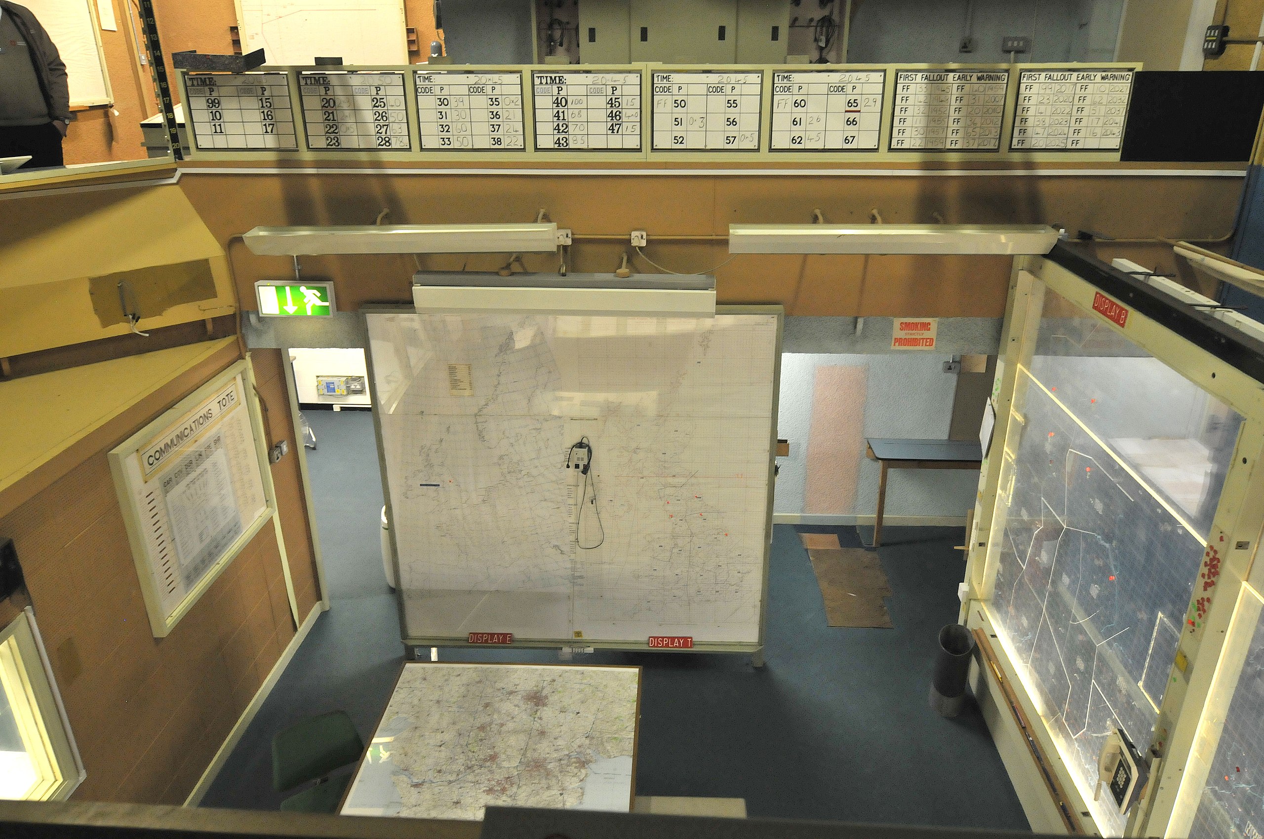 Stará vojenská riadiaca miestnosť s mapami a tabuľami, pripravená na strategické plánovanie a sledovanie operácií.