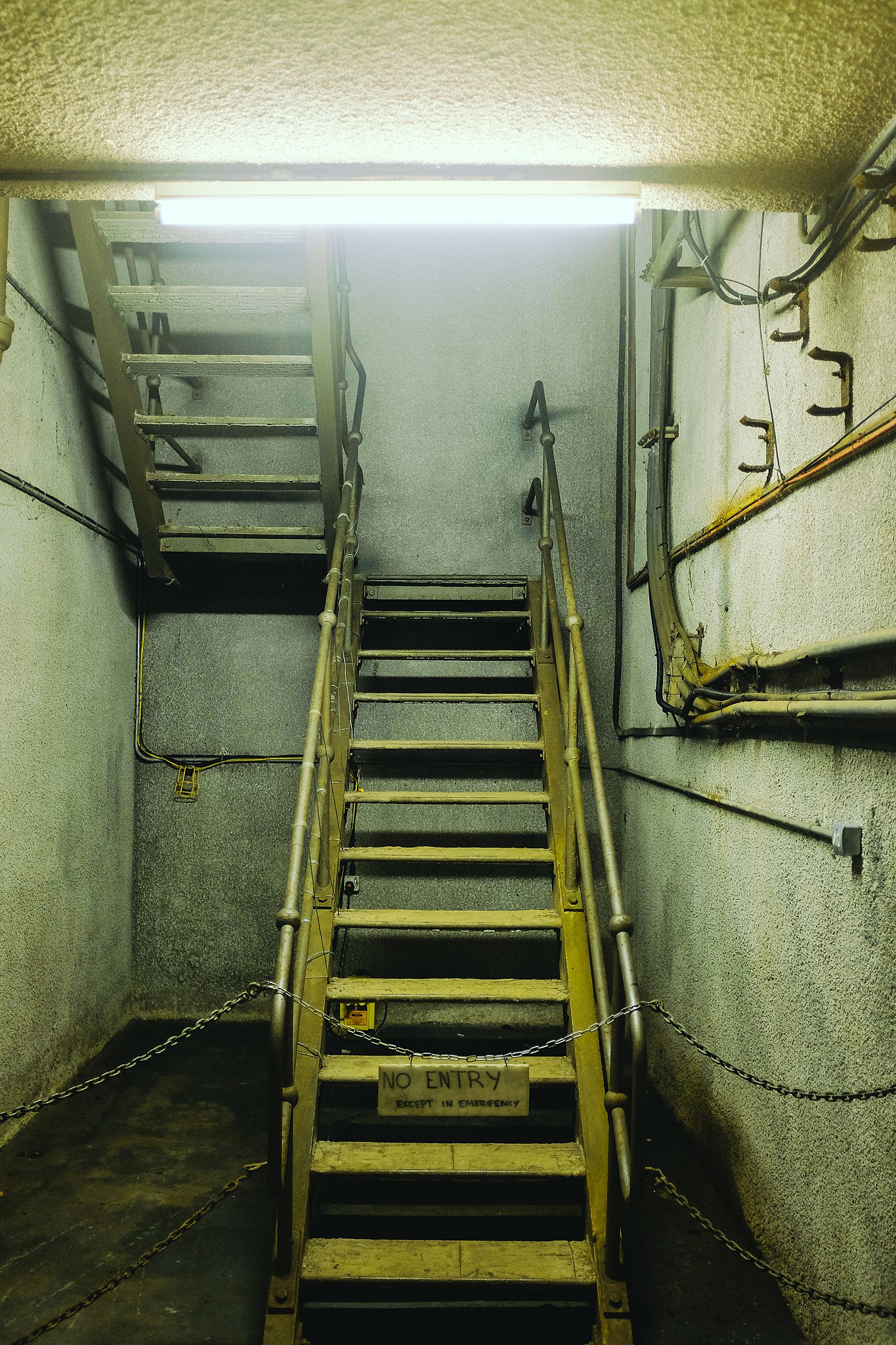 Priemyselné schodisko s nápisom No Entry, reťazami blokujúce prístup.