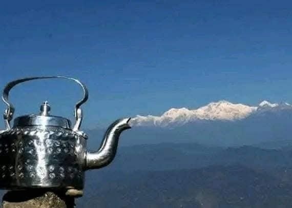 Strieborná kanvica na horách pod jasnou modrou oblohou s pohorím v diaľke.