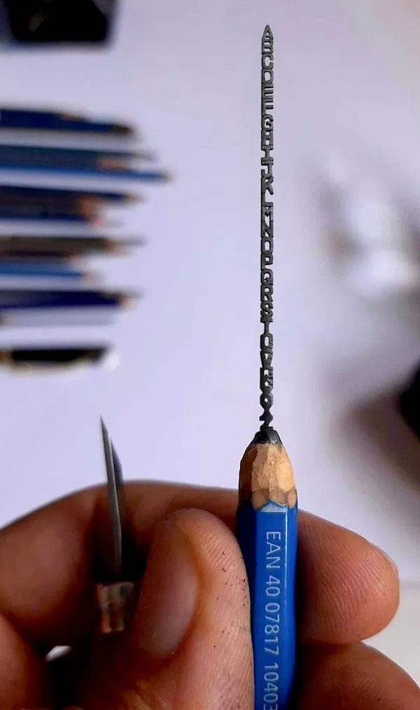 Ceruzka s mikroskopickým rezbárskym umením ukazujúcim celú abecedu na grafitovom jadre.