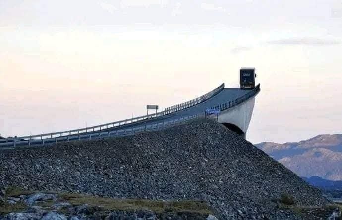 Kamión prechádza po strmotej časti známeho mostu na nórskom pobreží v krásnom večernom svetle.