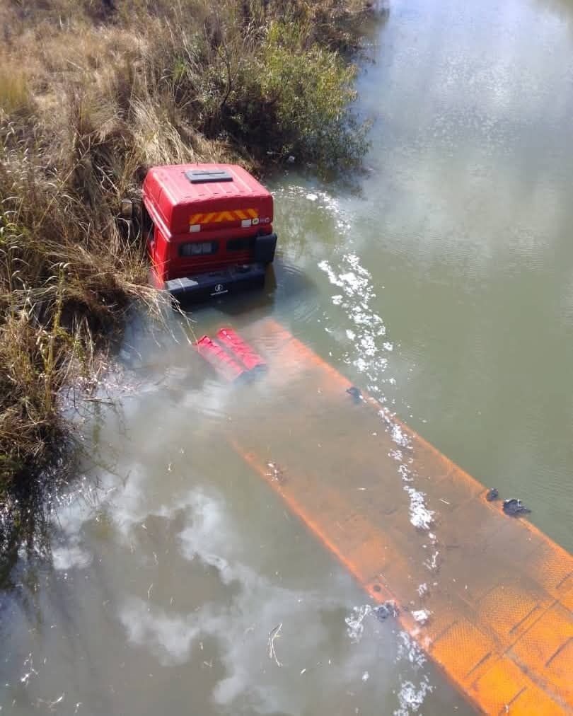 Nákladné vozidlo s návesom uviaznuté vo vodnom toku pri brehu, čiastočne ponorené vo vode.