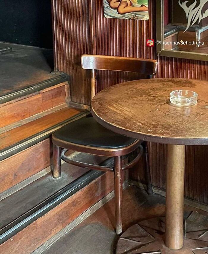 Stará drevená stolička za okrúhlym stolom v retro kaviarni s popolníkom na stole.