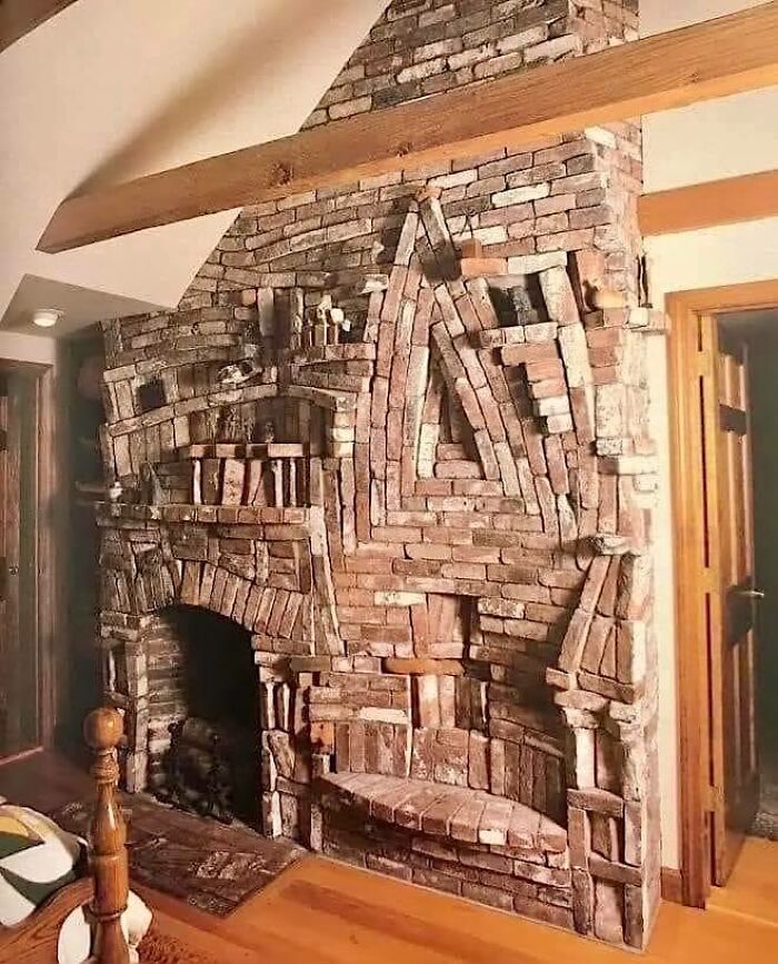 Unikátny tehlový krb s abstraktnými vzormi v rustikálnej obývačke, zvýrazňujúci interiérový dizajn.