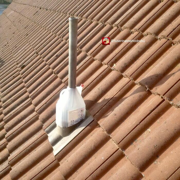 Plastová nádoba ako improvizovaná komínová rúra na červenej škridlovanej streche.