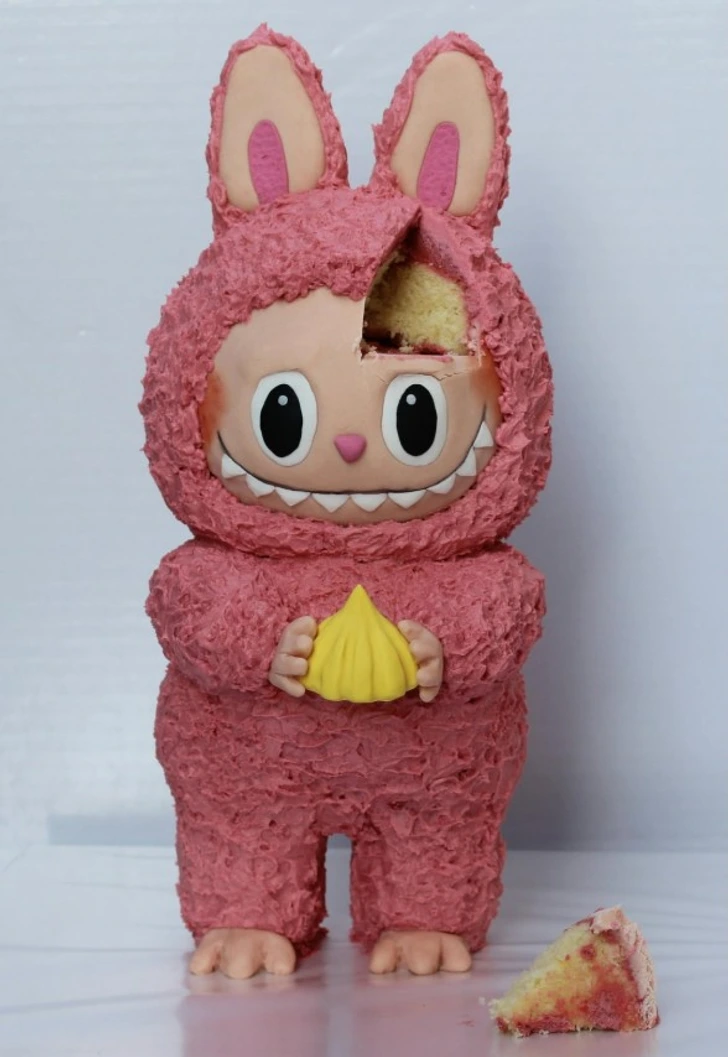 Ružový koláč v tvare zvieratka s ušami, chýbajúci kus odkryje vnútornú štruktúru. Kreatívne pečenie pre deti.