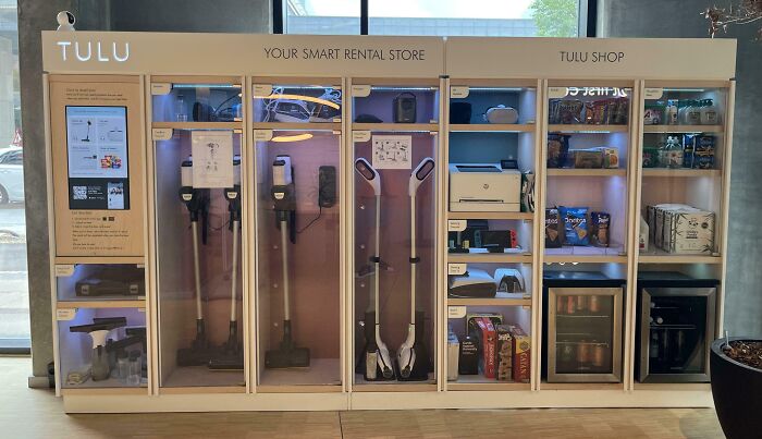 Automatizovaný regál TULU s rôznymi prenajímateľnými domácimi spotrebičmi a potravinami v modernom interiéri.
